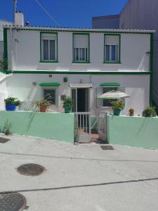 a white house with a green fence and an umbrella at Camino Bed and Breakfast Corme in Corme-Puerto +9 photos
