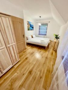 a living room with a white couch and wooden floors at Dom na zboczu góry in Brenna