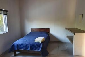 a small bedroom with a bed with a blue blanket at C10 Casa colmena 3 minutes from the beach and pool, 2 bedrooms. in La Peñita de Jaltemba