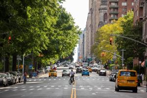 a busy city street with cars and a man riding a bike at Sunlit 2BR Central Park North elevator & laundry in New York