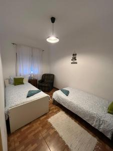 a bedroom with two beds and a chair in it at Paloma Caparica Beach in Costa da Caparica +60 photos