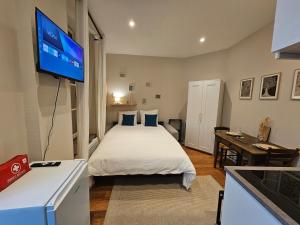 a bedroom with a bed and a flat screen tv at Aux'Cerfs - Studio coeur de ville in Auxerre