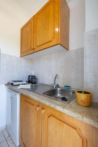 a kitchen with wooden cabinets and a sink at Palm Studios, 350m from Agios Sostis Beach, by ZanteWize in Zakynthos Town