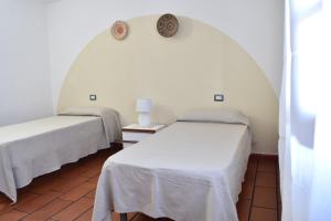 a room with two beds and a clock on the wall at Sardegna23 - Appartamento Vacanze - in Orosei