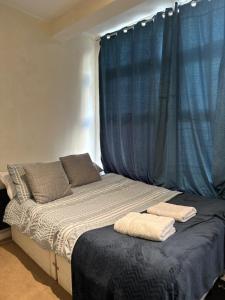 Una cama con cortinas azules y dos toallas. en Eastbourne Beachfront Apartments, en Eastbourne