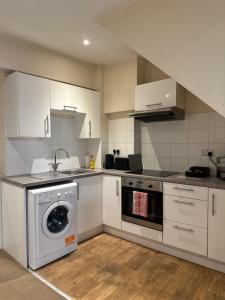 Una cocina con gabinetes blancos y lavadora. en Eastbourne Beachfront Apartments, en Eastbourne