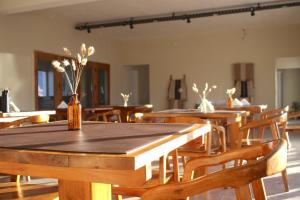 a room with wooden tables and chairs with flowers in bottles at Altos del Peñón in El Peñón