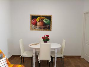 a white dining room table with chairs and a picture of fruit at casa abuelo bacallado in Las Lagunas