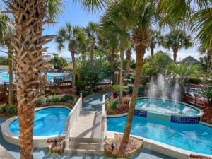 a pool with a fountain in a resort with palm trees at Beach Cove Resort in Myrtle Beach +43 photos