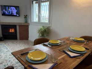 Una mesa de madera con platos amarillos encima y una chimenea. en Casa Pradillo, en Trujillo