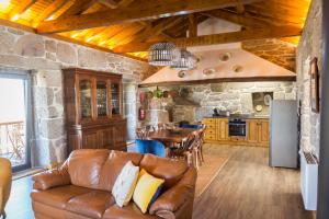 a living room with a leather couch and a kitchen at Valados do Outeiro - Casas de Campo in Valença