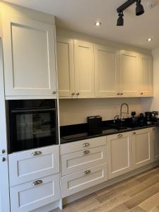 eine Küche mit weißen Schränken und schwarzen Arbeitsplatten in der Unterkunft Trevor Street in Holywood