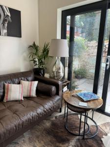 ein Wohnzimmer mit einer Ledercouch und einem Tisch in der Unterkunft Trevor Street in Holywood