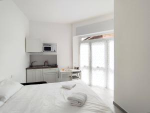 a white bedroom with a bed and a kitchen at Residence Mario Bianco in Milan