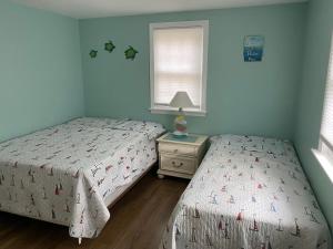 1 Schlafzimmer mit 2 Betten, einem Nachttisch und einem Fenster in der Unterkunft Willows Cottage East in Dennis Port