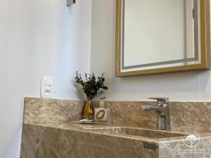 a bathroom sink with a vase of flowers on it at Apartamento Novo Aconchegante e Moderno em Canela in Canela +34 photos
