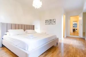 a white bedroom with a large white bed and a chandelier at Elegantis Monti Royal Apartment with private terrace in Rome