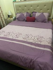 a bed with a purple comforter with a redinylinylinylinylinyl at ALFUTTAIN Vacation Homes Rental in Dubai