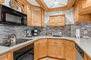 a kitchen with wooden cabinets and a black microwave at Lodge Tower 387 Three Bedroom Residence in Vail
