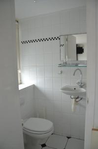 a white bathroom with a toilet and a sink at Pension 't hofje 350 meter van het strand in Noordwijk aan Zee