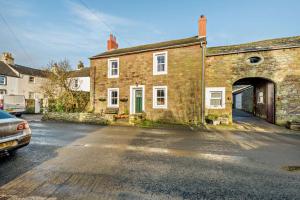 an old brick house with an archway in a street at Pear Tree Cottage - Solway Coast in Bowness-on-Solway