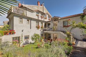 a large white house with flowers in the yard at Apartments Ljiljana in Pula