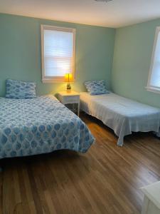 ein Schlafzimmer mit zwei Betten und einem Tisch mit Lampe in der Unterkunft Willows Cottage West in Dennis Port