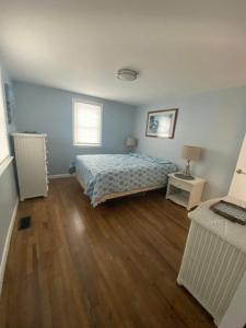 ein Schlafzimmer mit einem Bett und einem Holzboden in der Unterkunft Willows Cottage West in Dennis Port