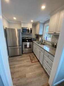 eine Küche mit weißen Schränken und Geräten aus Edelstahl in der Unterkunft Willows Cottage West in Dennis Port