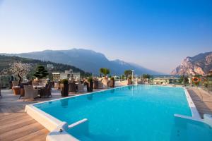 a swimming pool with chairs and mountains in the background at Hotel Kristal Palace - Tonelli Hotels - Adult Friendly in Riva del Garda +65 photos