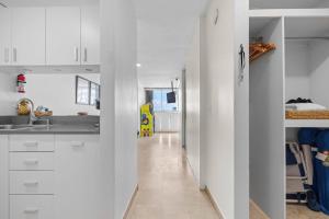 una cocina con armarios blancos y un pasillo en Otium Pool Beach Access, en San Juan