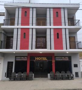 een rood-wit hotel met stoelen ervoor bij Costa del sol Termas Ex Lucas III in Termas de Río Hondo