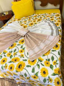 a bed with a flower comforter with a bow on it at Hotel Pousada Mozini's in Tupã