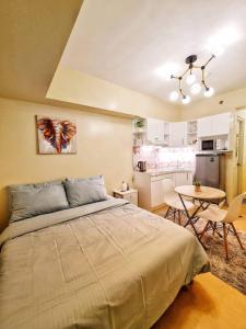 a bedroom with a bed and a table and a kitchen at Condo at the Heart of Davao in Avida Towers Davao in Davao City