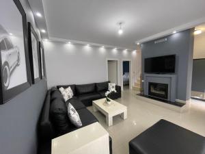 a living room with a black leather couch and a fireplace at Casa Di SI in Përmet