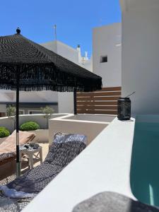 a patio with two chairs and an umbrella at Island Charm Imerovigli Apartment in Imerovigli
