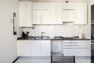 a white kitchen with white cabinets and a sink at Venice Shore Apartment in Venice +4 photos