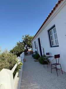 a white house with chairs and a table outside at Casa de Campo in Vila Nova de Cacela