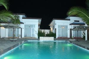 a swimming pool in front of a house at night at Zanzibar Luxury Bungalows in Tongoni