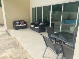 a patio with a table and chairs and a couch at Alto padrão piscina Praia Mococa in Caraguatatuba