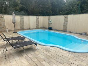 a large blue swimming pool with two chairs and a fence at Alto padrão piscina Praia Mococa in Caraguatatuba