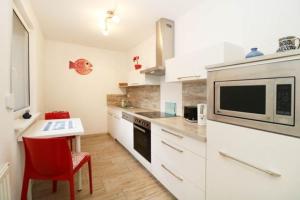 une cuisine avec des armoires blanches, une table et un micro-ondes dans l'établissement Haus Oertel Koje 23 Trassenheide Usedom, à Trassenheide