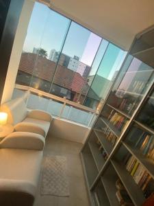 a living room with a white couch and a large window at Duplex Acolhedor - Duas quadras do Mar Centro in Tramandaí