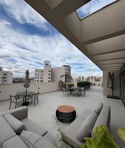 eine Terrasse mit Sofas und Tischen auf dem Dach in der Unterkunft Casa Pantuso no coração de BH in Belo Horizonte