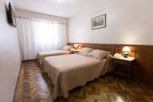 a hotel room with two beds and a television at Hotel Parlamento in Buenos Aires