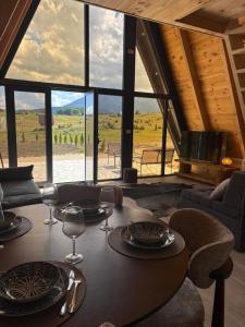 a dining room with a table and a large room with windows at Vista Montis in Žabljak