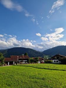 a green field with houses and mountains in the background at Das Stangenäcker in Unterammergau