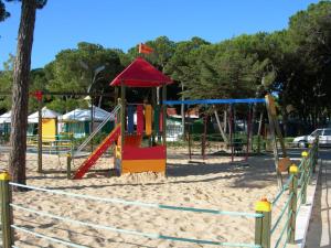 a playground with a swing set in the sand at Parque de Campismo Orbitur Costa de Caparica in Costa da Caparica