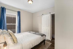 a bedroom with a bed with blue curtains and a window at The Metropolitan Manor-new Corporate Apt Downtown in Grand Rapids
