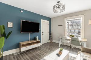 a living room with a flat screen tv on a blue wall at The Metropolitan Manor-new Corporate Apt Downtown in Grand Rapids